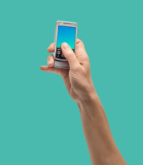 Hand holds retro mobile phone against vibrant green background, showcasing vintage technology.