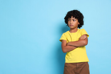 Portrait of sad little boy on light blue background, space for text