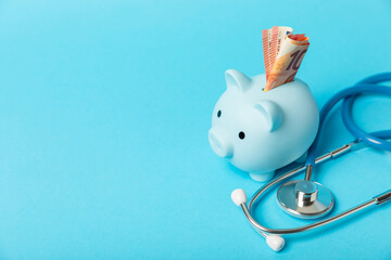 Medical costs, financial concept, health insurance. Stethoscope over dollar bills. Money and piggy bank. Medical care. Health care financial checkup or saving for medical insurance costs concept.