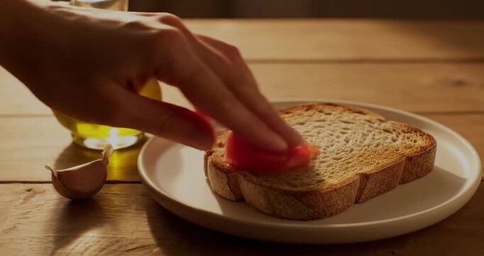 Rubbing tomato on toasted rustic bread slice. Pan con tomate concept.