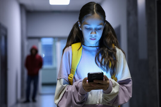 Child in danger. Girl using phone while man stalking her indoors, selective focus