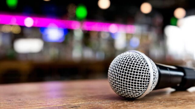 Dynamic microphone lying on a wooden bar, waiting for a performance in a vibrant nightlife venue with bokeh lights