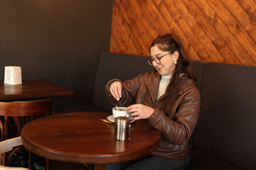 Young woman in glasses drinking tea at a table in a cafe