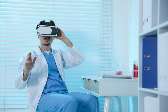 Modern technology. Doctor using virtual reality headset at desk in office. Space for text