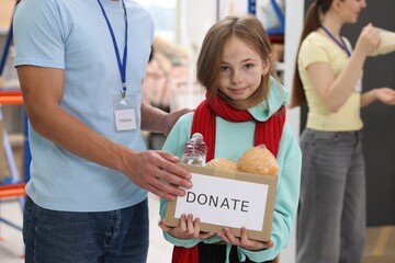 Volunteer giving box of donations to homeless girl in shelter, closeup