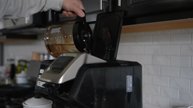 man pouring water into coffee machine reservoir