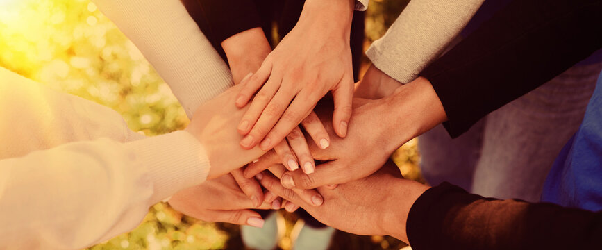 Group of volunteers stacking hands outdoors on sunny day, closeup. Banner design