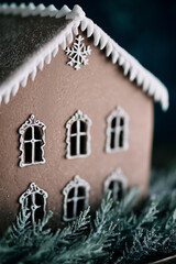 Gingerbread house with white icing details and frosted greenery creating cozy winter holiday atmosphere concept of christmas decor festive sweets food styling