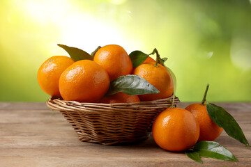Fresh juicy tangerines on wooden table against blurred green background