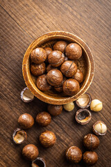 Tasty macadamia nuts in bowl on wooden table. Top view.