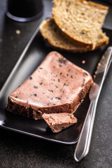 Liver pate with cranberries on black plate.