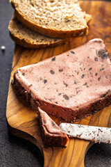 Liver pate with cranberries on wooden cutting board.