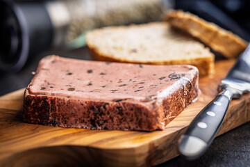 Liver pate with cranberries on wooden cutting board.