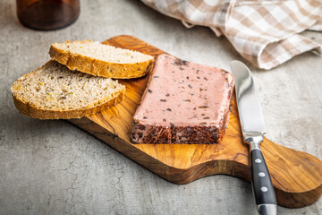 Liver pate with cranberries on wooden cutting board.