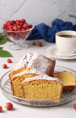Sliced homemade milk cake, dusted with powdered sugar, and cup of coffee