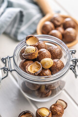 Tasty macadamia nuts in jar on white table.