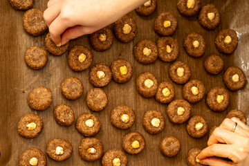 Top view of woman and child placing hazelnuts on cookies together. Family holiday tradition and teamwork