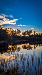 Vertical Autumn Sunset Photograph of a Finnish Lake with Perfect Water Reflection.