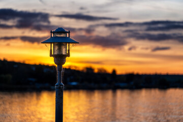 Stra&szlig;enlaterne im Retro-Stil am Ufer von einem See bei Sonnenuntergang