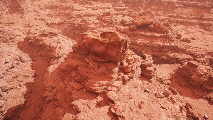 A stunning rocky formation rises from the barren red terrain, surrounded by rugged cliffs and dust. The vibrant colors and geological features create a mesmerizing natural spectacle.