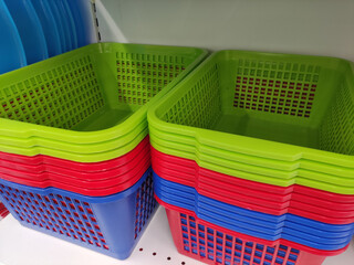 Colorful plastic storage baskets in vibrant green, red, and blue stacked neatly on a shelf, showcasing organization and home decor options
