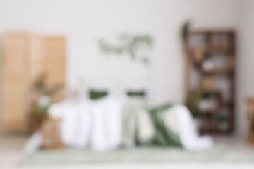 Blurred view of light bedroom with shelf unit and green plants