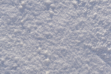 Top view photo of snow on the ground in the sunny winter morning. Winter white pure clean snow background texture with soft snowflakes on cold day.