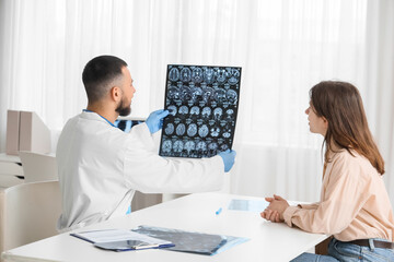 Male doctor showing MRI scan of head to patient in clinic