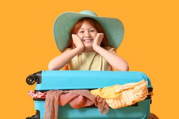 Cute girl with suitcase on yellow background. Travel concept