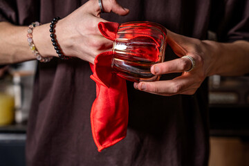 Hands polishing glass cup with red cloth