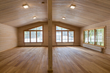 Spacious interior of a modern wooden cabin with ample natural light streaming through large windows