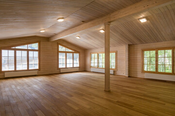 Bright and inviting room with wooden walls and floors, featuring large windows that let in plenty of sunlight.