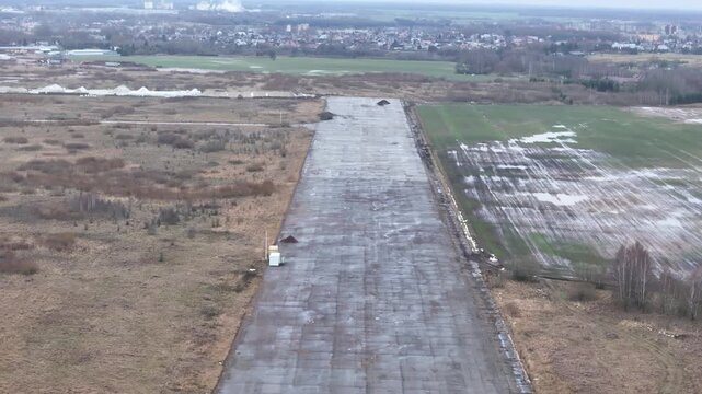 A deserted concrete runway of a former Soviet military airbase in Kedainiai, Lithuania. Overcast sky, rural fields, and decaying aviation infrastructure