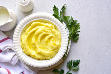 Mashed potato with cheese and herb in a white bowl. Top view with copy space.
