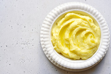 Mashed potato with cheese and herb in a white bowl. Top view with copy space.