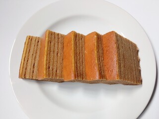 slice of lapis legit cake on plate. close-up of indonesian layer cake lapis legit slices on white plate.