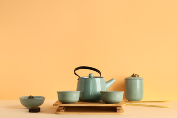 Tray with teapot, cups of tea and dry pressed puer leaves on color background