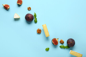 Composition with pieces of tasty Camembert cheese, fresh ripe figs and basil leaves on blue...