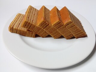slice of lapis legit cake on plate. close-up of indonesian layer cake lapis legit slices on white plate.
