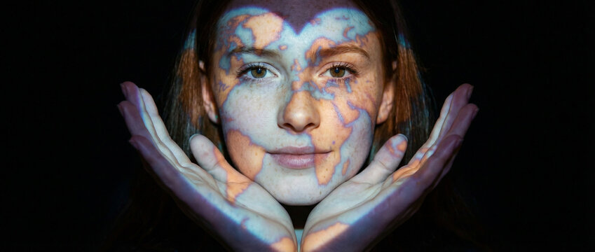 young woman's face illuminated with world map projection, symbolizing global connection