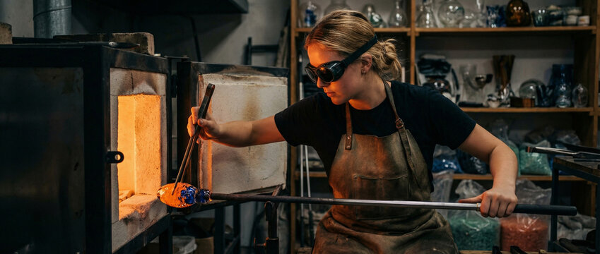 skilled artisan crafting glassware in a dimly lit workshop with furnace and tools
