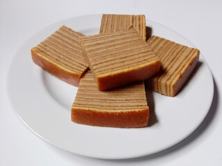 close-up of indonesian layer cake lapis legit slices on white plate.