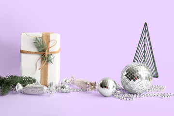 Composition with gift box, disco balls and Christmas decor on lilac background