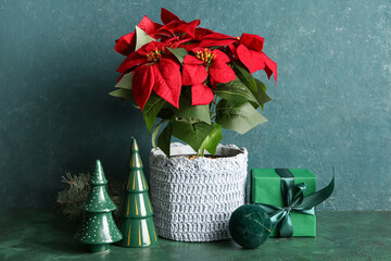 Christmas plant poinsettia, gift box and decorations on green grunge table