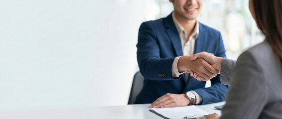 Business partners shaking hands after successful meeting, closing a deal, discussing project, negotiating agreement, or signing contract in a modern office environment