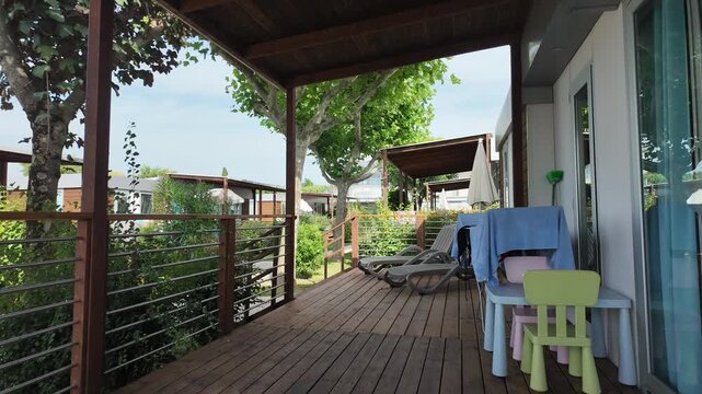 Lazise, Italy - June 18, 2024 - timelapse of wooden deck with chairs and table at a holiday park cabin on a sunny day