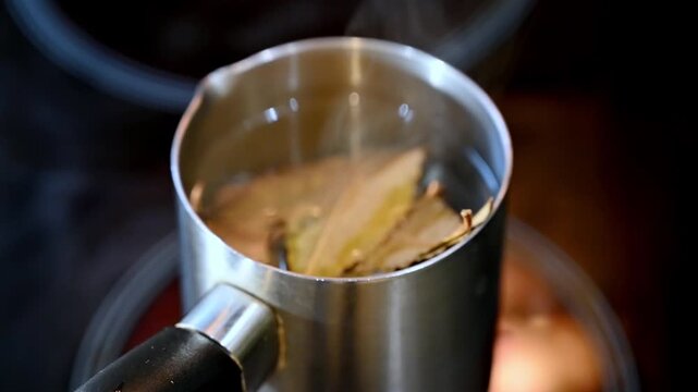 Aromatic bay leaf decoction brewing in a pot on an electric stove.