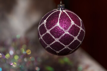 A close-up of a shiny purple Christmas ornament with a white net pattern