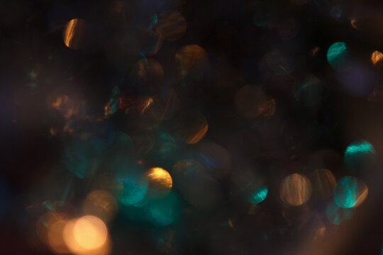 Abstract bokeh background with colorful light spots in shades of blue, orange, and green. - Powered by Adobe