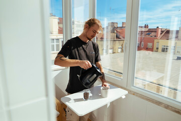 Young individual rapidly brews coffee with city rooftop view behind